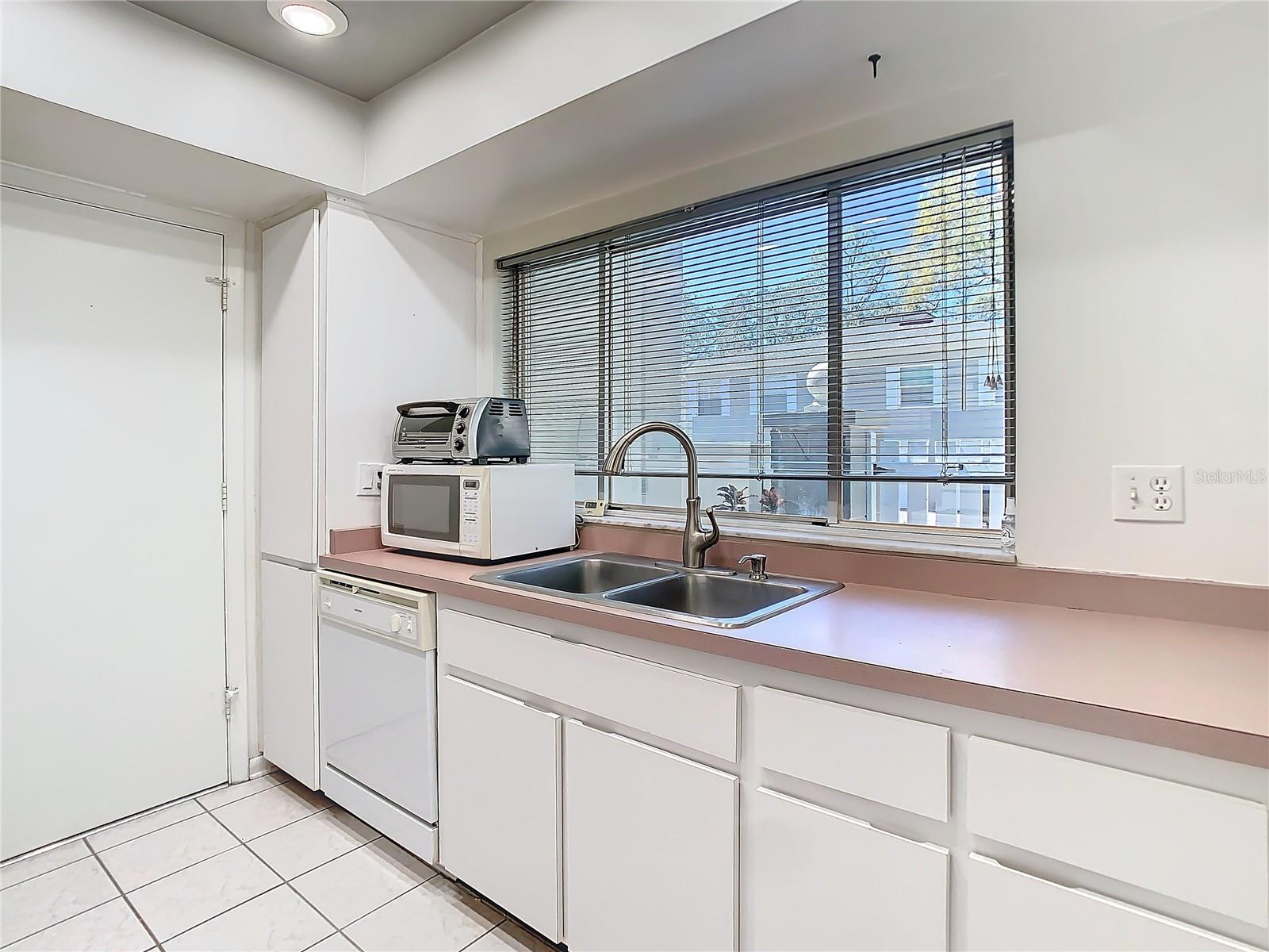 Kitchen showing dishwasher, sink and window overlooking private courtyard