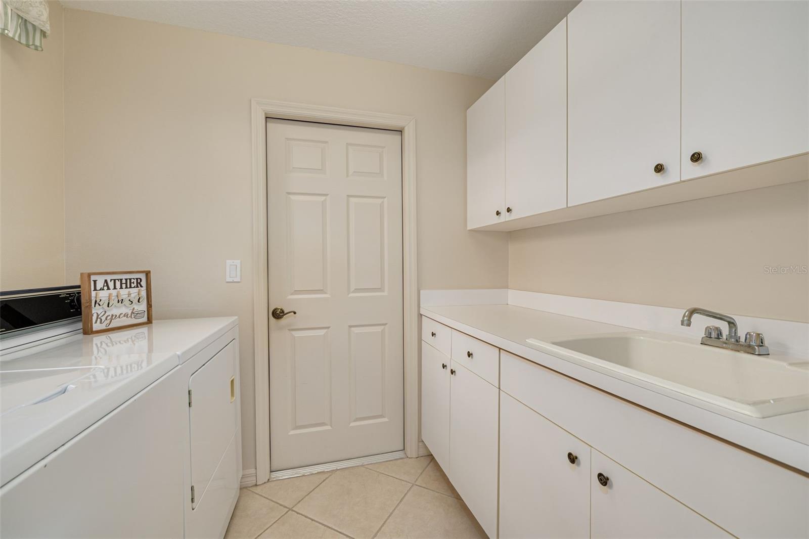 Inside laundry room - sink, cabinets and the washer and dryer convey!