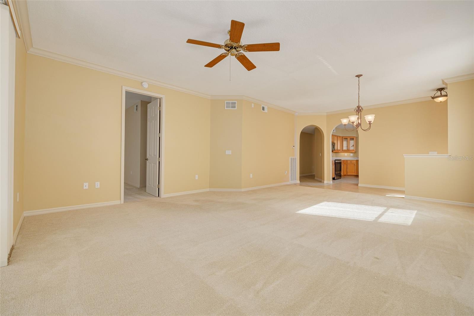 LR with door to primary bedroom on left, entrance to kitchen on right