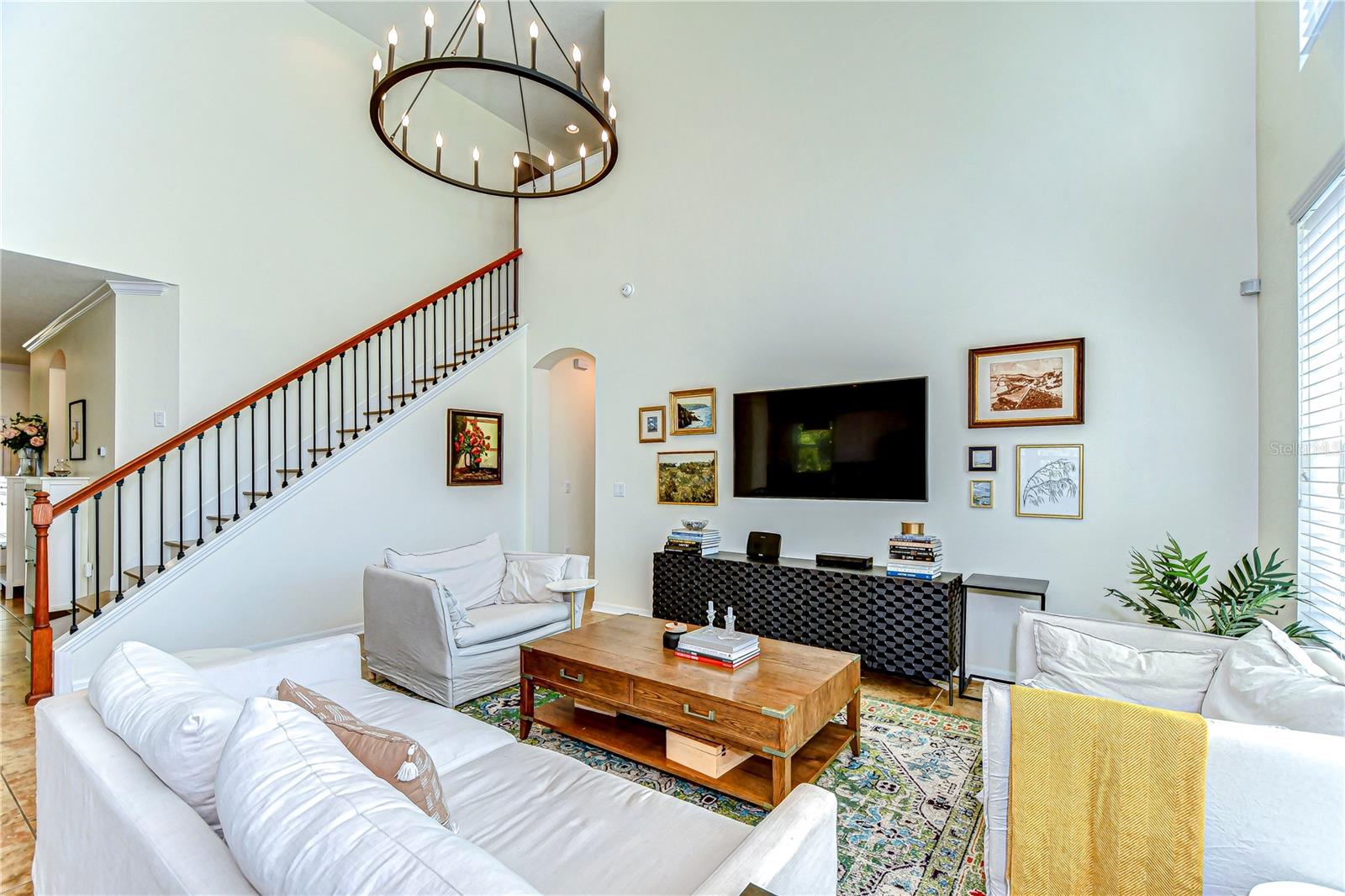 Bask in modern elegance with this light-filled living room, featuring soaring ceilings and a striking chandelier.