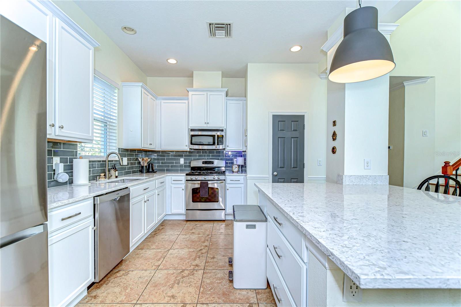 Step into this bright, modern kitchen featuring sleek stainless steel appliances, chic subway tile backsplash, and ample quartz countertops.