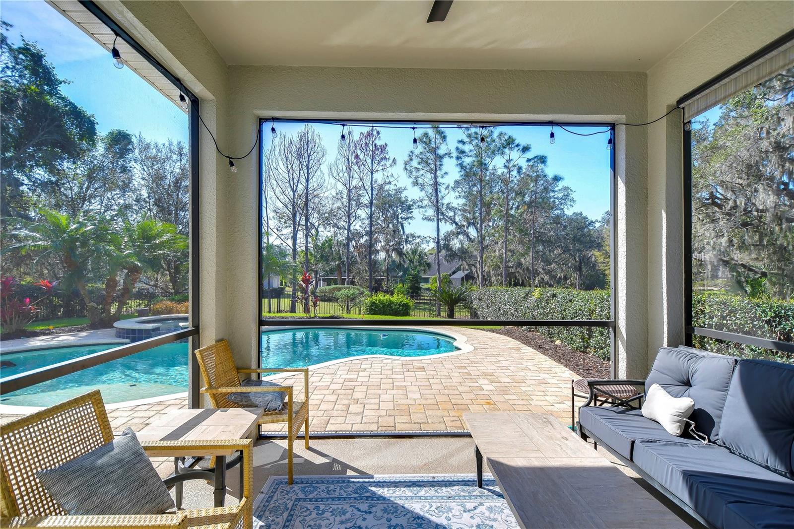 Enjoy serene mornings in your screened lanai, overlooking the sparkling pool and lush greenery.