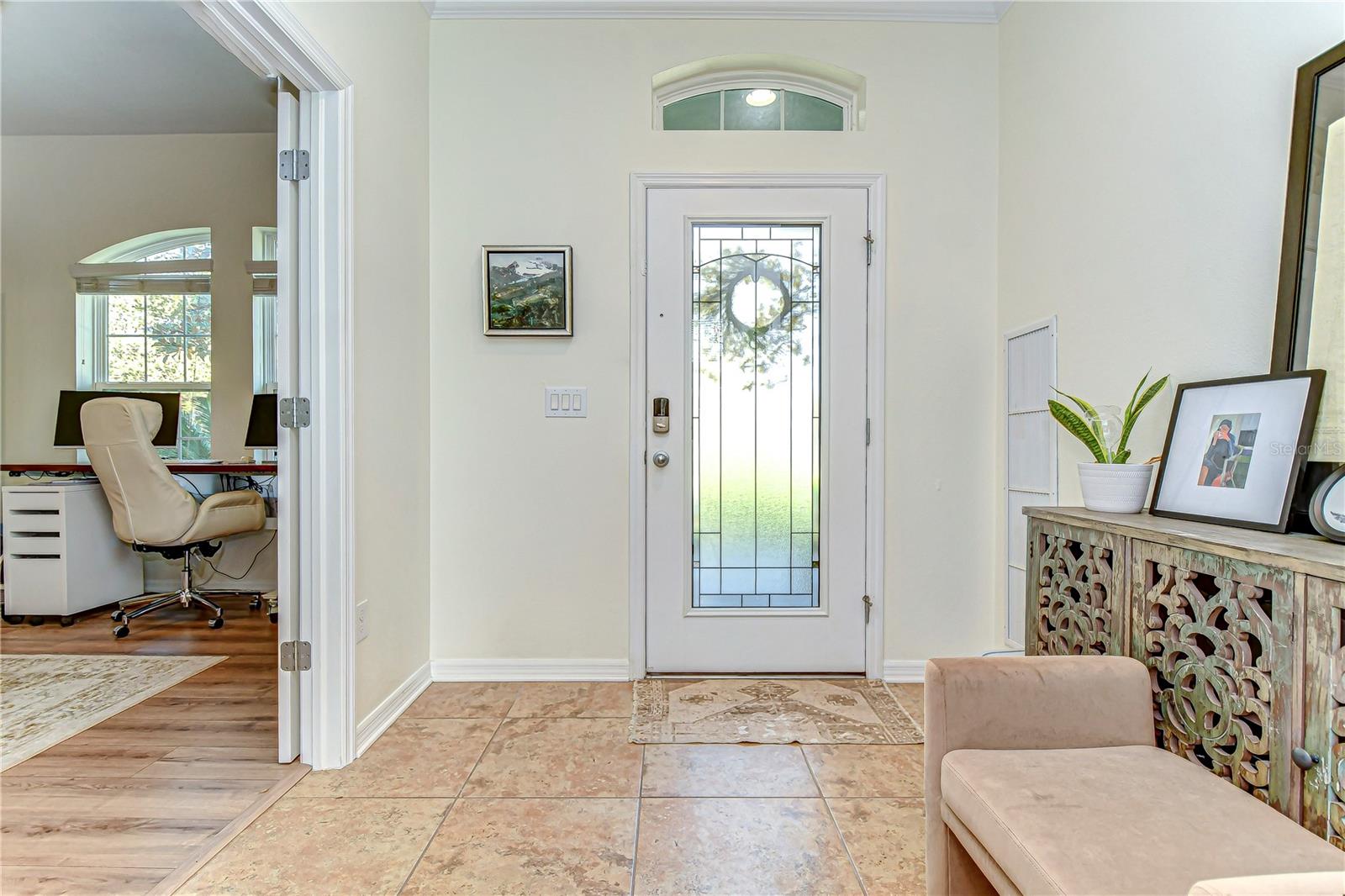 This elegant entryway features natural light and a sneak peek into the home office