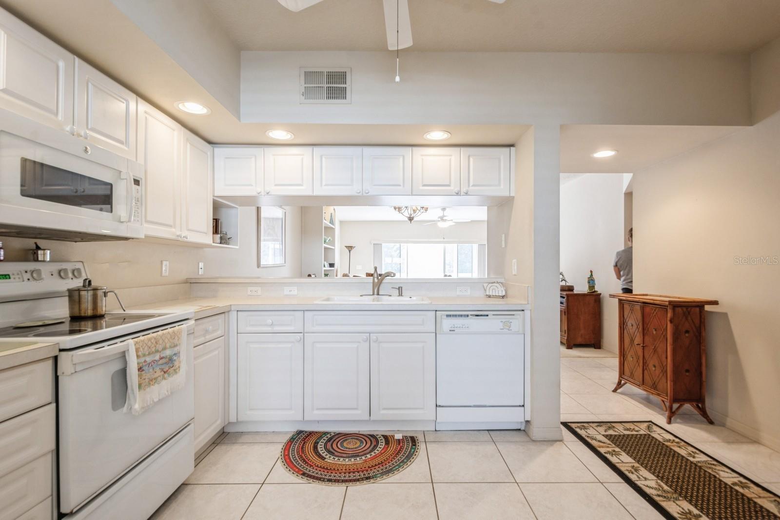 Kitchen open to living/dining areas. Natural light flows through from the sliding doors for a bright and cheery home