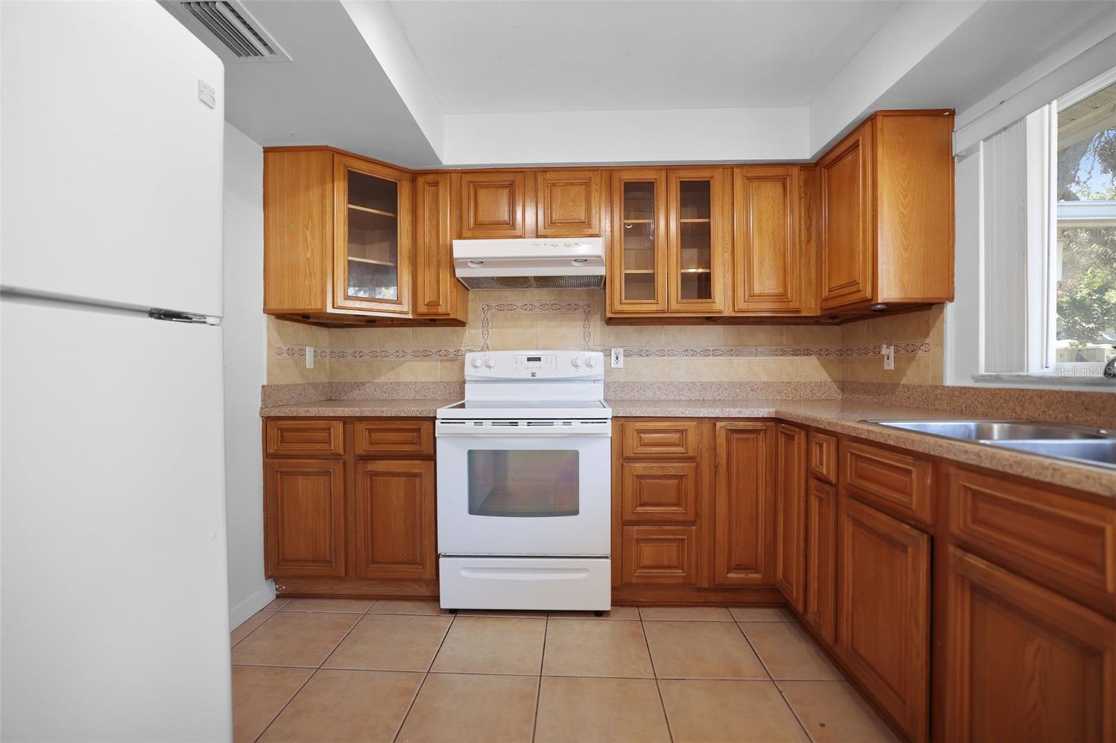 Kitchen with coiffured ceiling, tile floors and view to large front yard