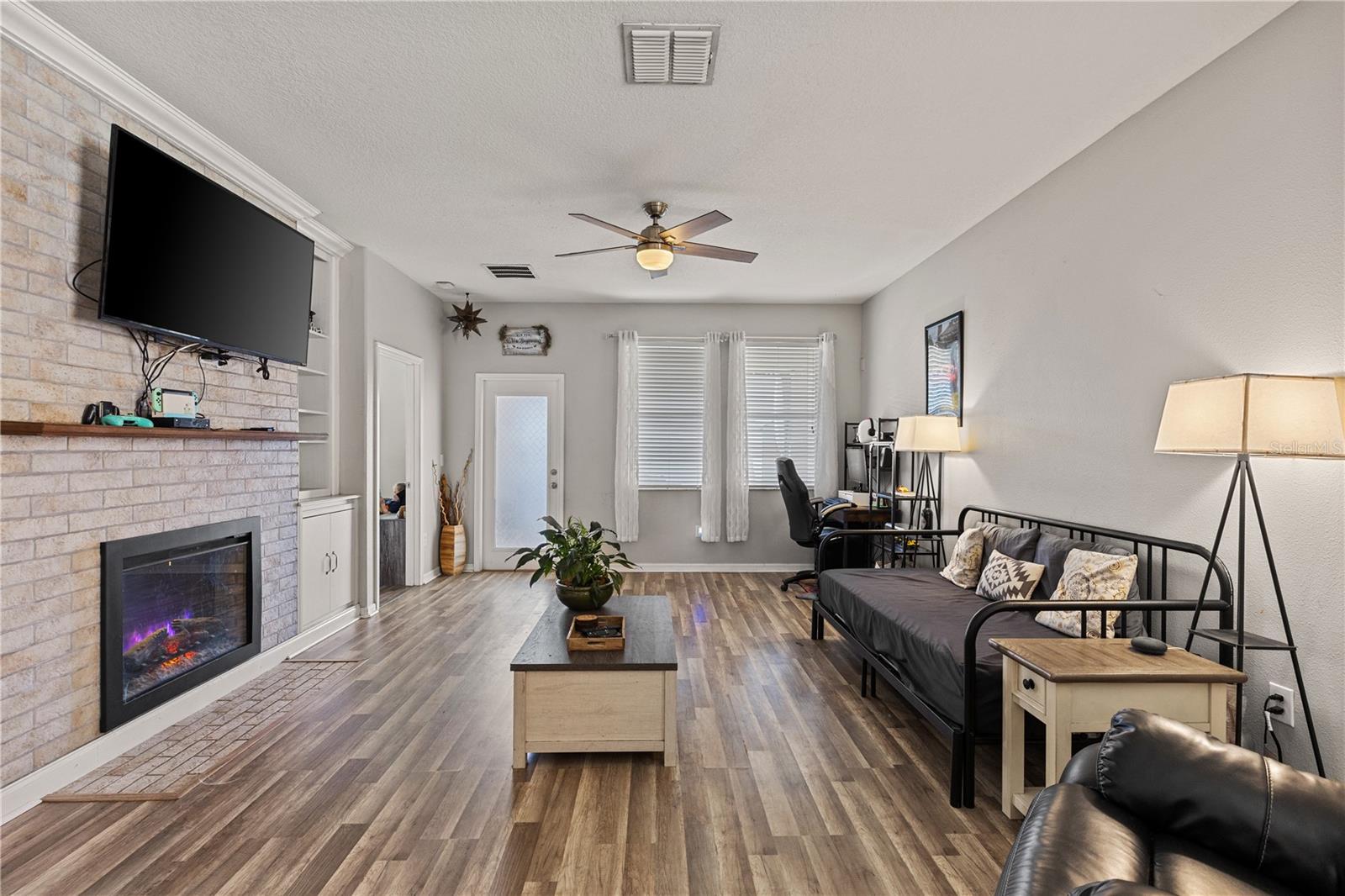 The living room boasts a white brick accent wall with an electric fireplace