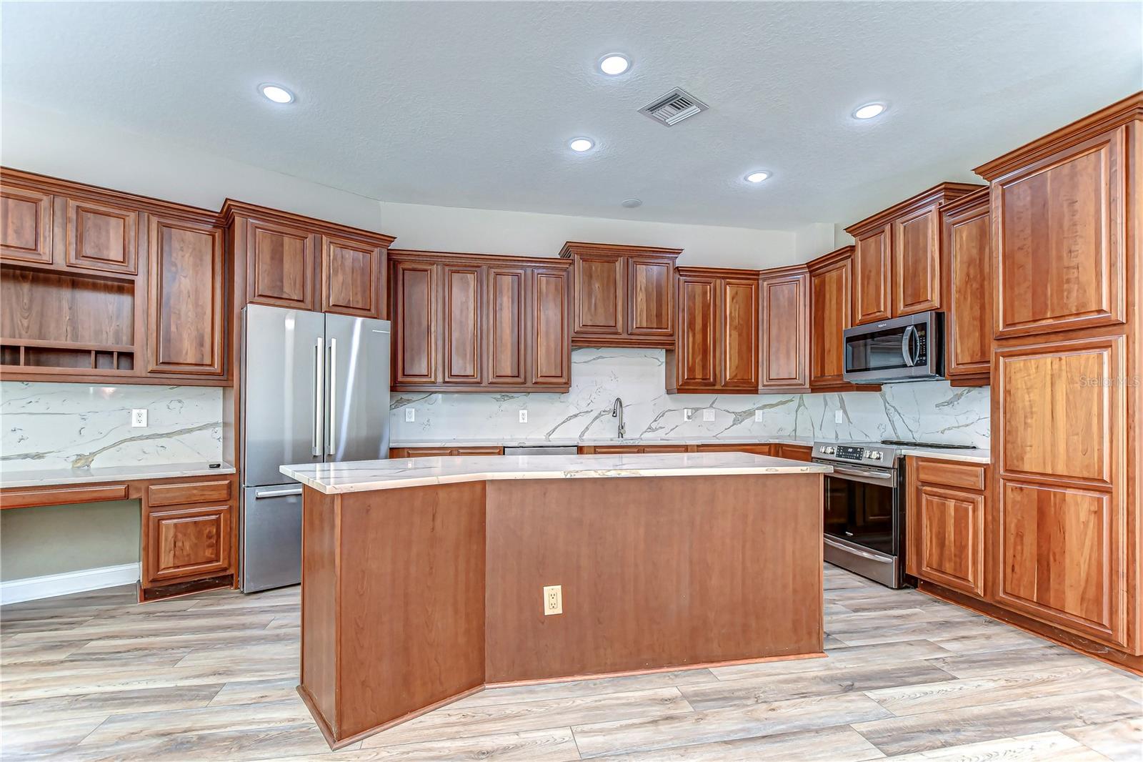 This stunning kitchen, featuring rich wood cabinetry and sleek stainless steel appliances, is perfect for culinary adventures.