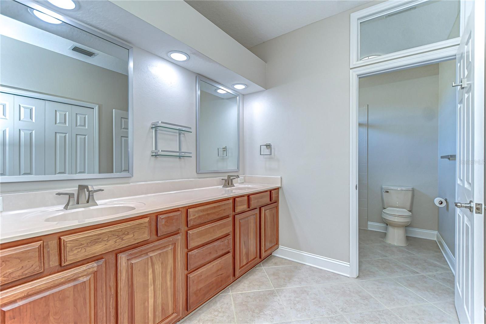 Step into elegance with this spacious bathroom featuring dual sinks and modern fixtures.