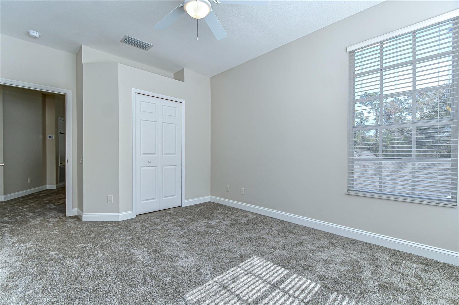 This inviting bedroom promises endless possibilities with its soft carpet and abundant natural light.