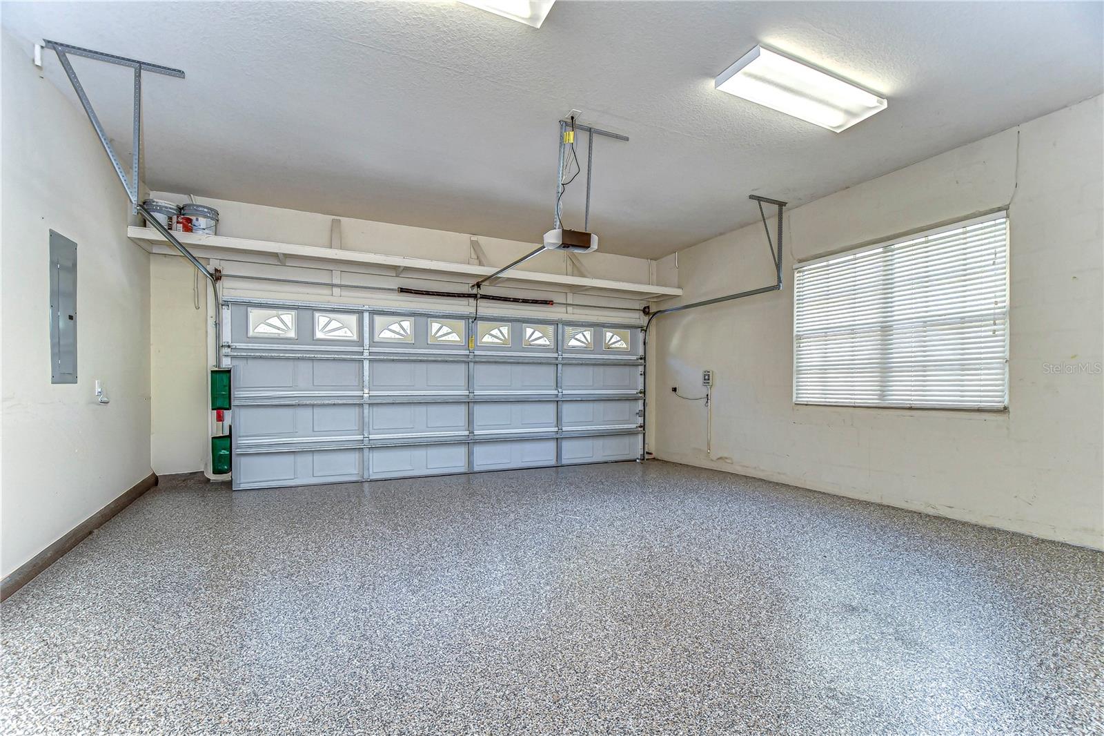 Spacious two-car garage with sleek epoxy flooring and natural light. Perfect for your cars or a weekend DIY project space.