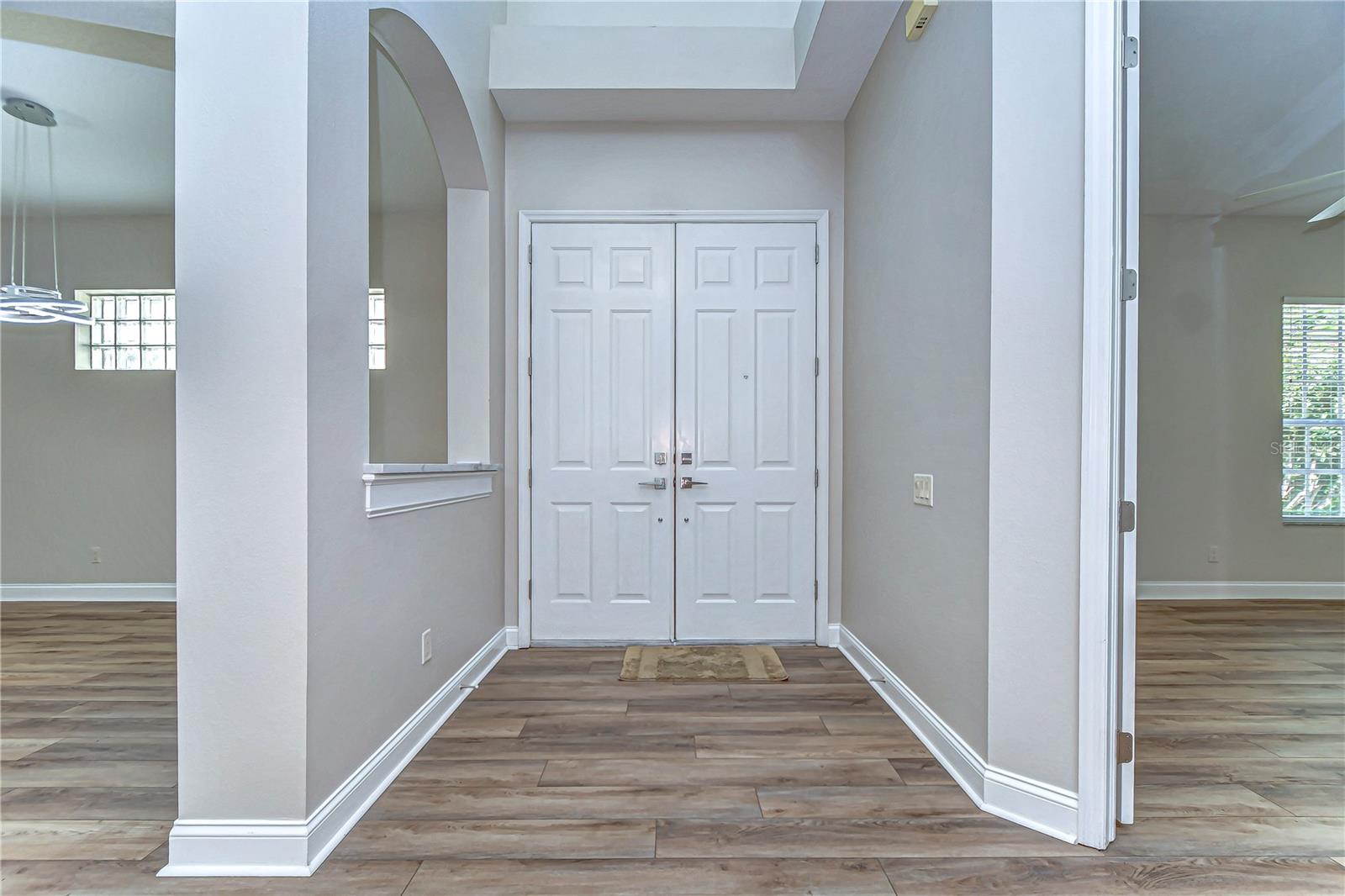 Step into elegance through this grand entryway, featuring sleek flooring and tasteful archways