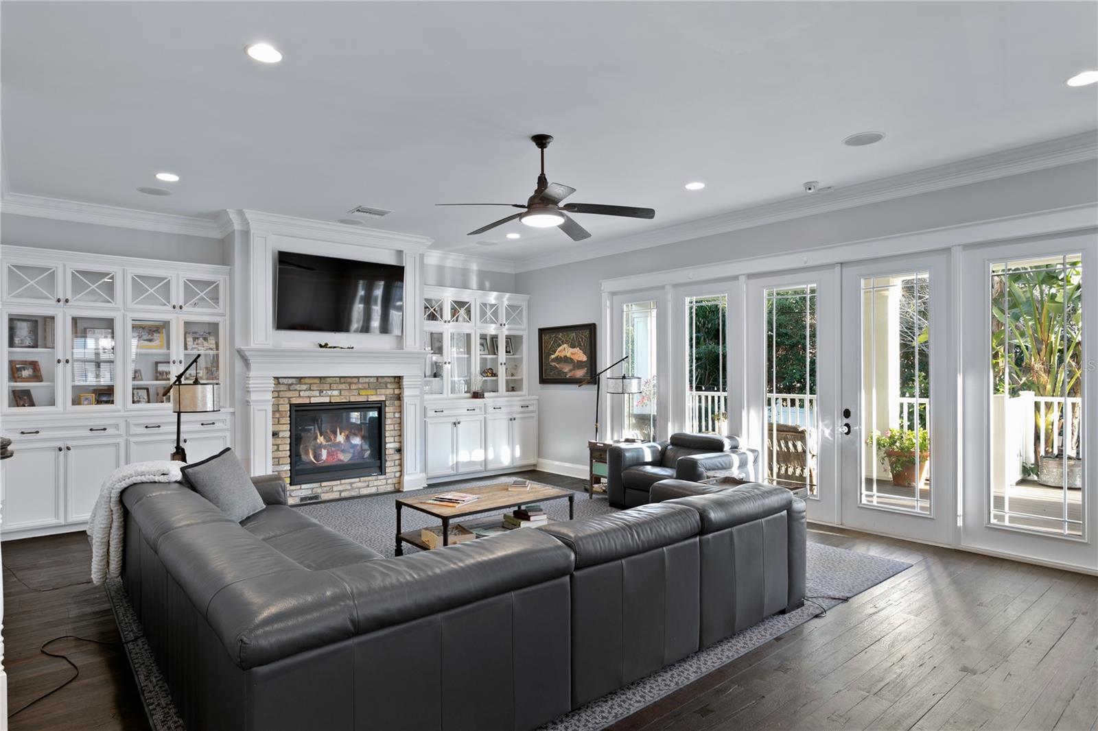 The spacious Great Room has oversized large French doors enhancing the natural light in the space, gas fireplace, flanked by custom built ins for enhanced storage and showcasing whatever makes your heart sing.