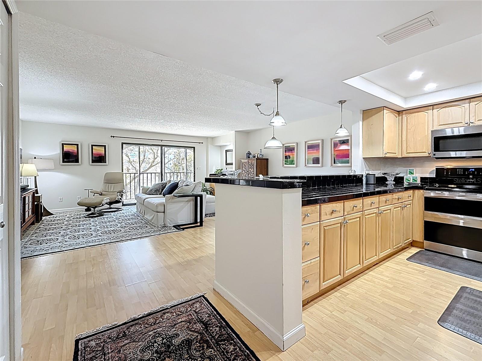 The spacious living area is filled with natural light from both the kitchen window and the large balcony sliding glass doors.