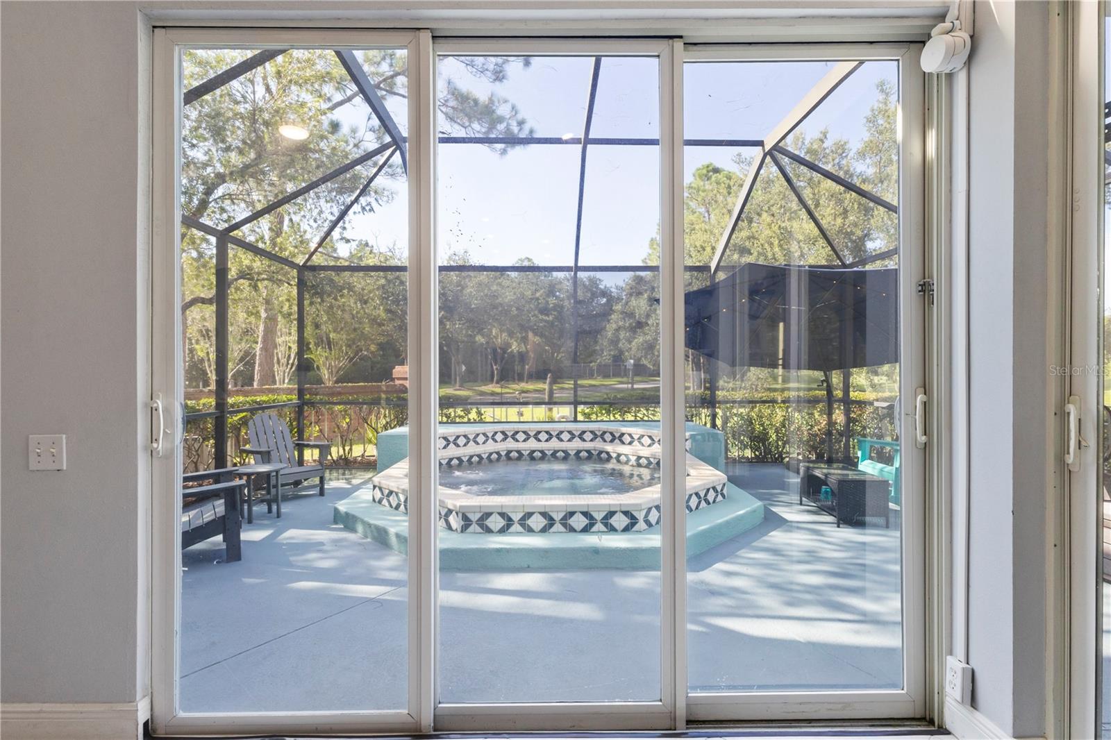 Triple slider leading to caged patio with hot tub