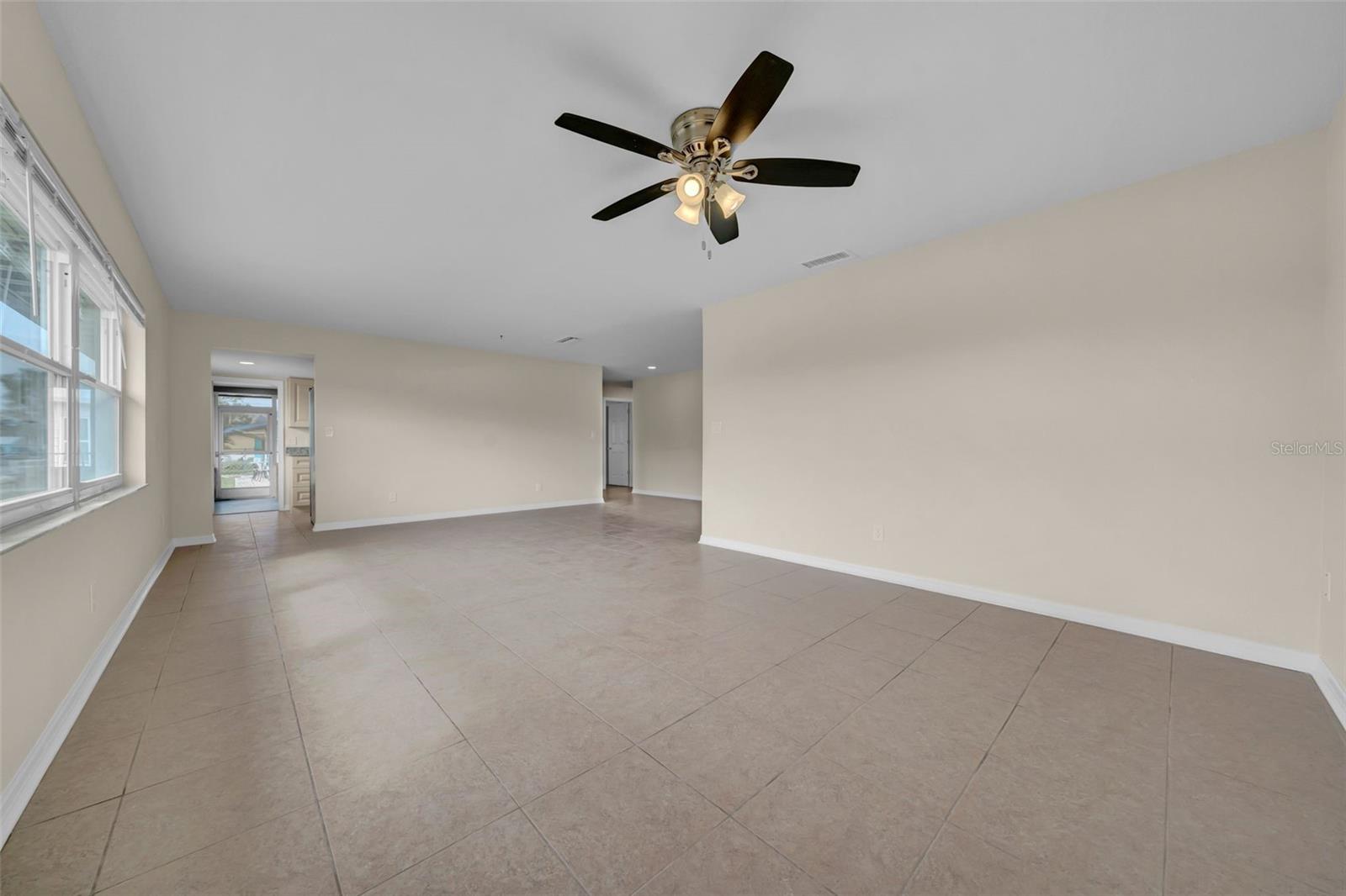 Livingroom with kitchen and a door that leads out to the enclosed lanai