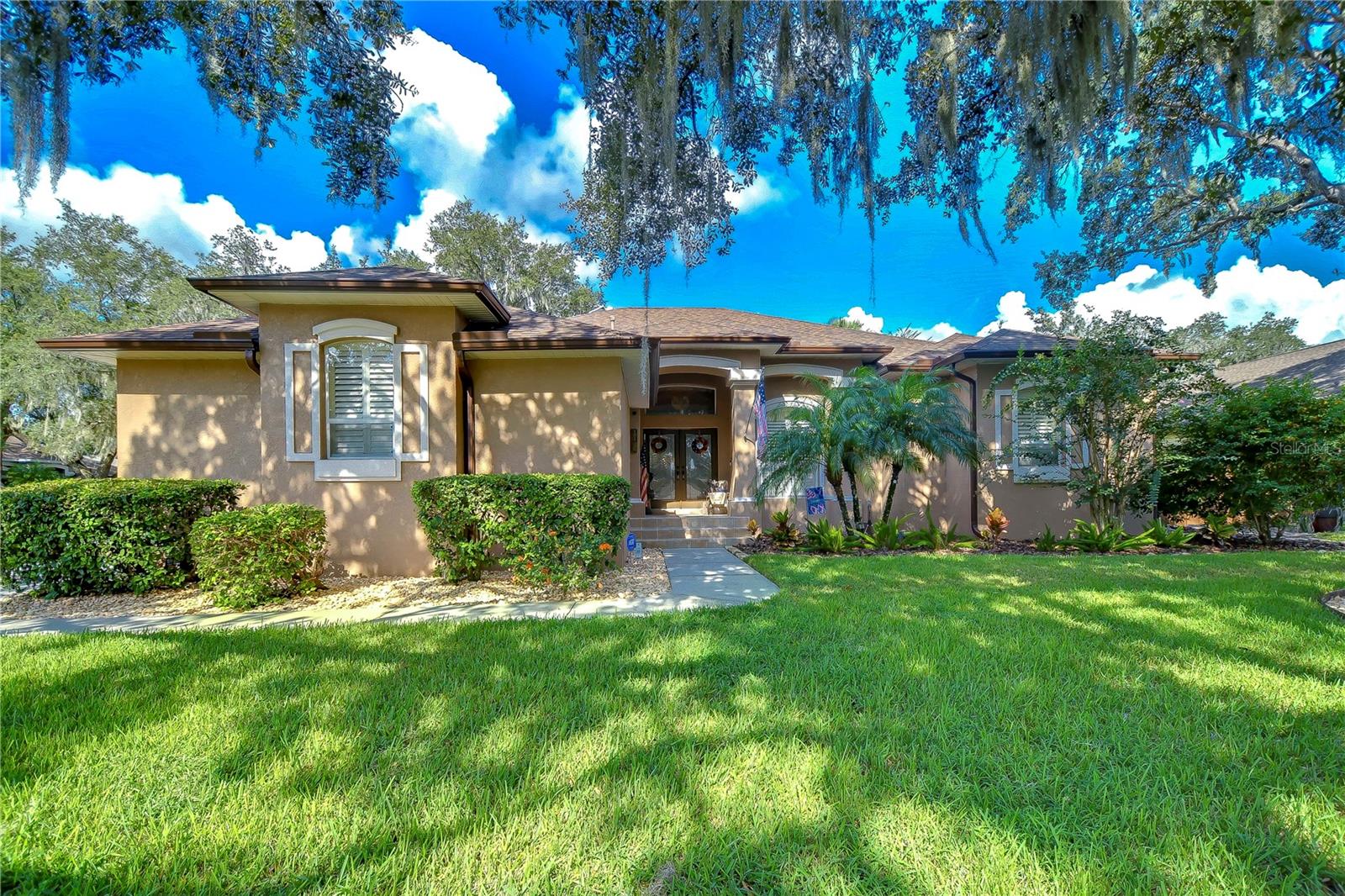 Nestled under a canopy of lush trees, this charming home invites you with its tasteful landscaping and elegant entrance