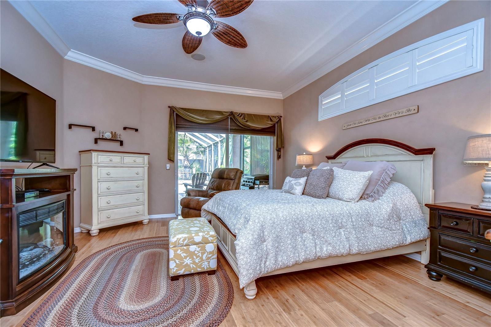 Step into luxury in this serene primary bedroom, featuring elegant crown molding and direct access to the patio.