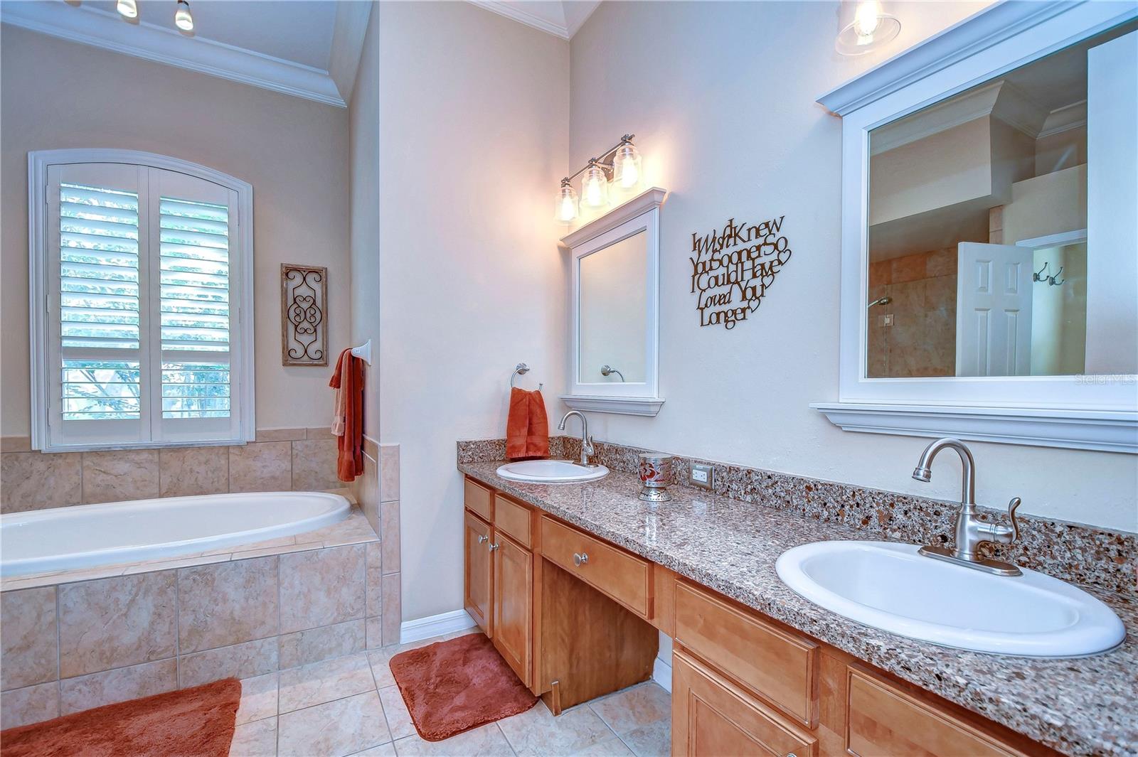 Relax in a spa-like primary bathroom featuring double sinks, a luxurious soaking tub, and elegant lighting.