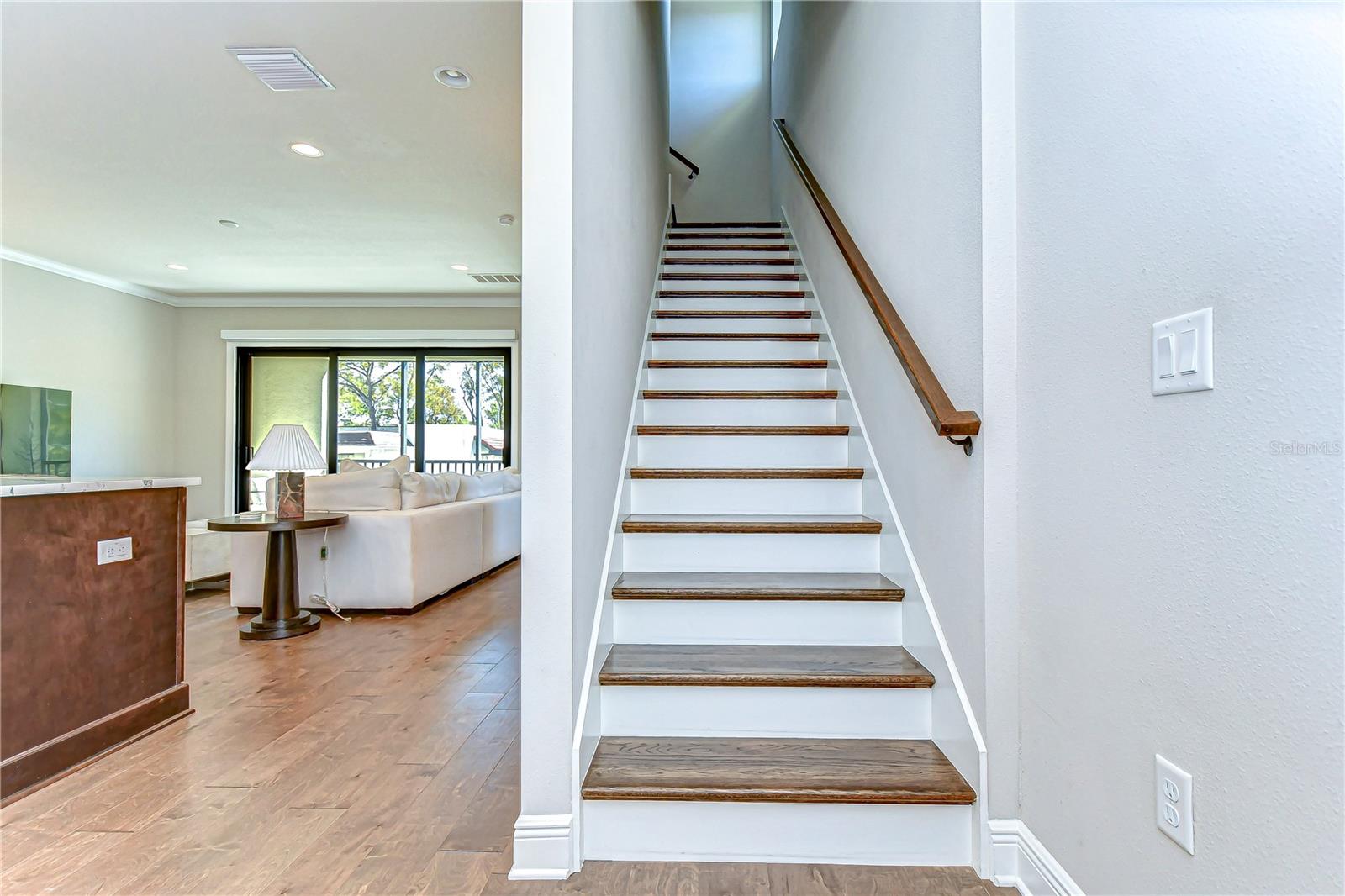 Step into elegance with sleek hardwood floors and an inviting open-plan living area. These stunning stairs lead you to a realm of comfort and style in this exquisite Tampa home.