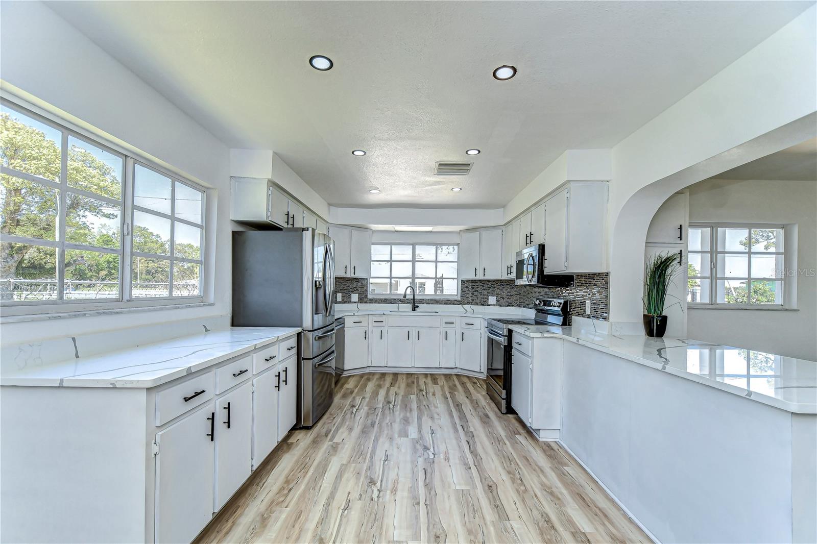 Gorgeous natural light floods the room through large windows, creating an inviting atmosphere perfect for both casual breakfasts and gourmet dinners.