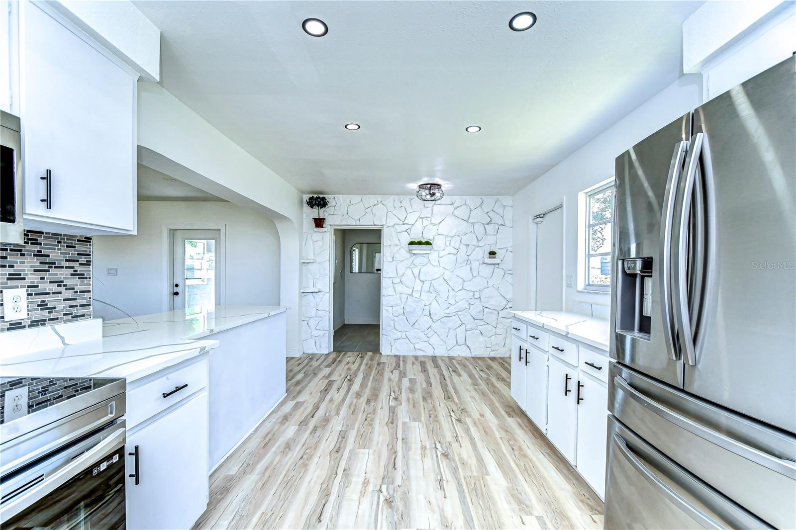 Step into this dazzling kitchen where modern meets chic with sleek stainless steel appliances and a striking stone accent wall.