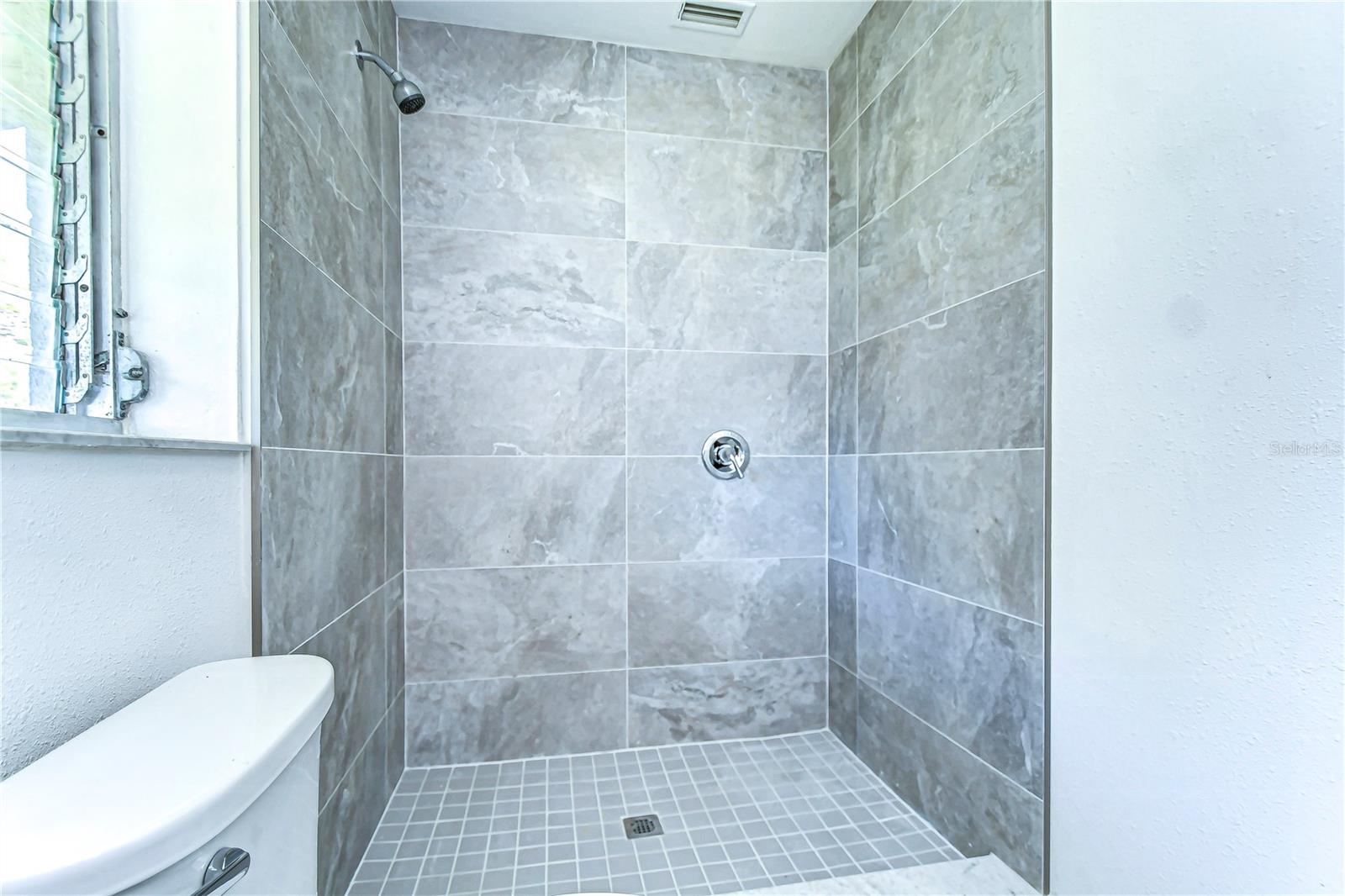 Step into your own personal spa-like retreat with this stylish, modern shower space. The elegant gray tiles and sleek fixtures offer a serene setting for relaxation and rejuvenation.