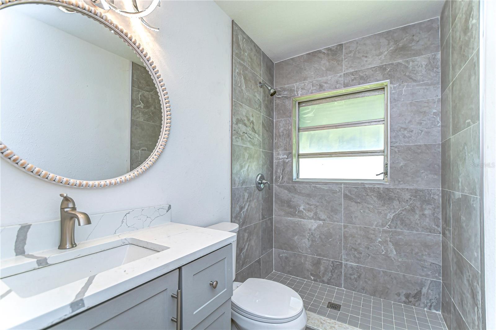 Step into serene elegance with this sleek bathroom featuring stylish gray tiles and a contemporary vanity