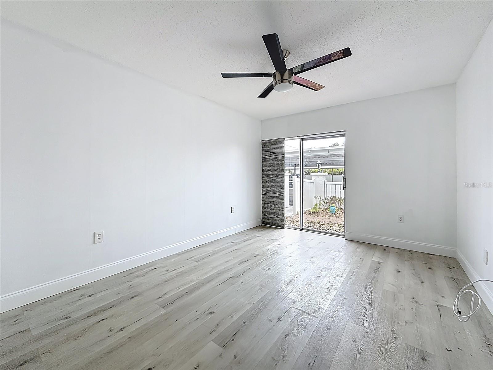 You are at the Guest bedroom door. Shades are on the sliding glass doors which lead to the front porch. Wall closet to your left ( out of view in this picture)