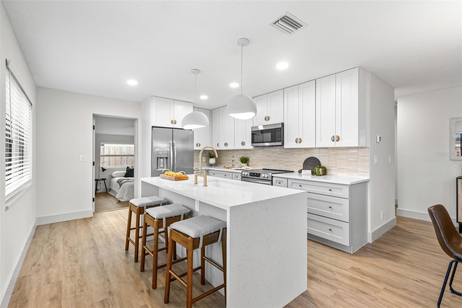Updated kitchen with Quartz waterfall edges, stainless steelappliances, brass hardware