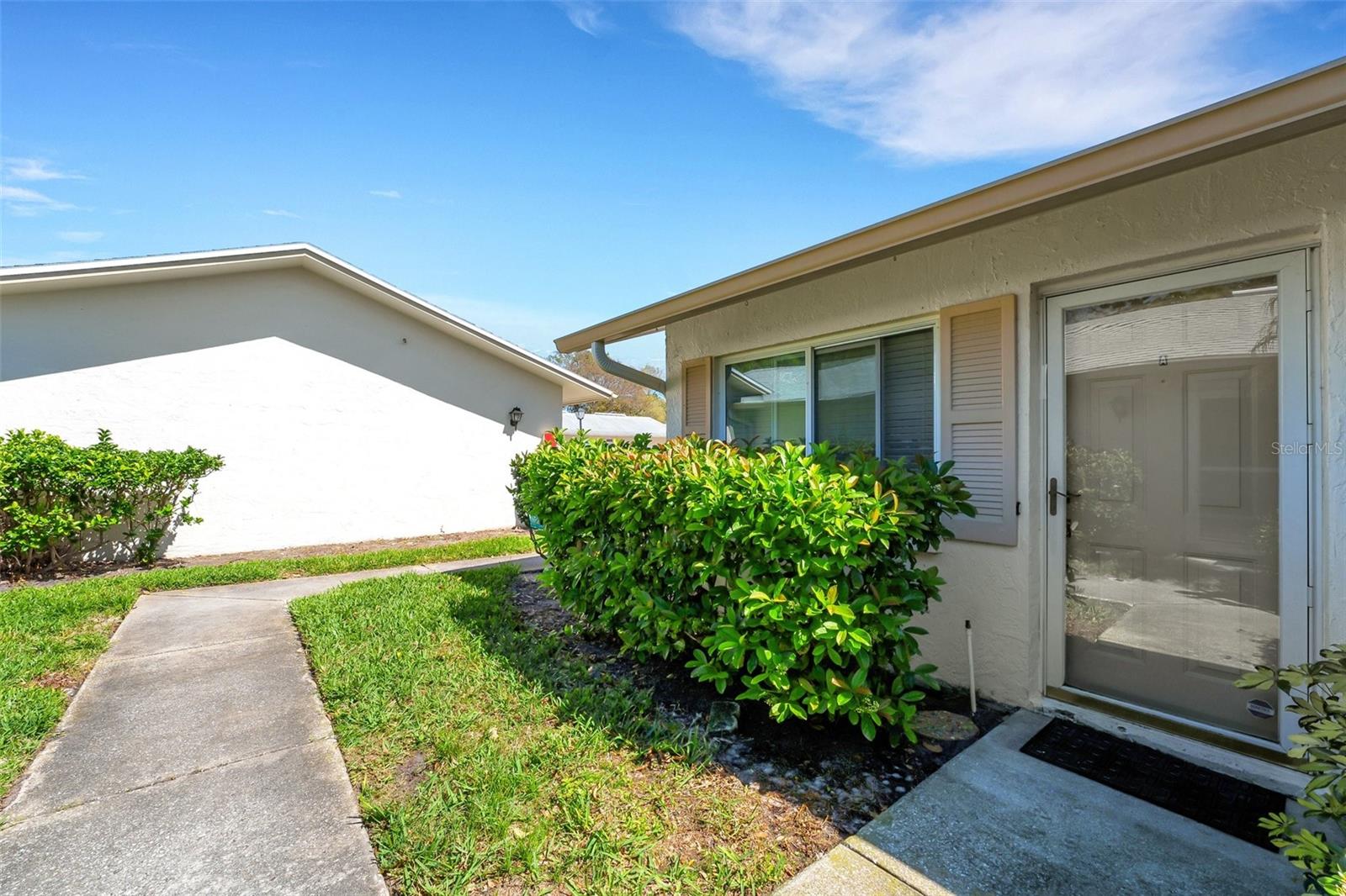 This inviting villa features a beautifully landscaped walkway leading up to the front door, offering a warm and welcoming first impression. The garage, located just a short distance away, provides easy access.