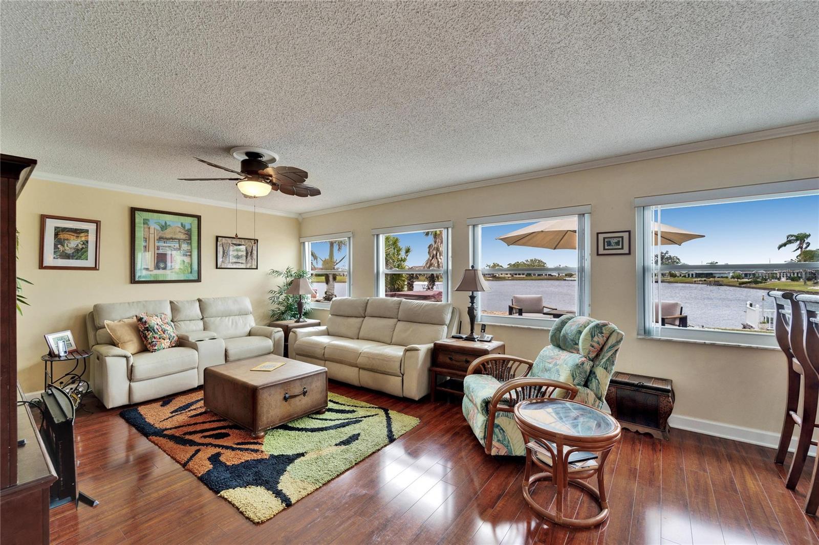 Living room has multiple windows overlooking the lanai and lake