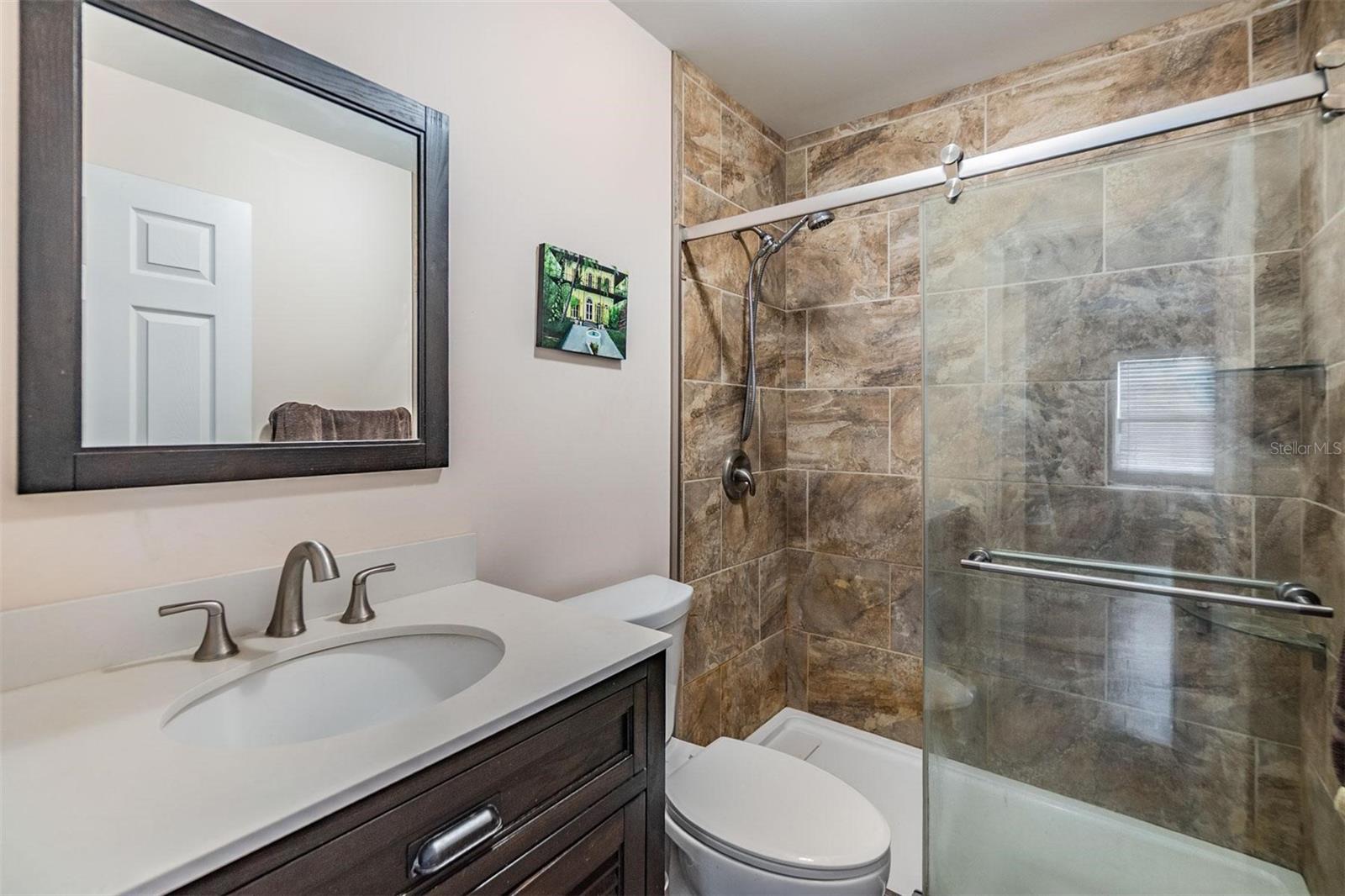 Primary ensuite bathroom with elegant tile accents, stand up shower and stylish vanity.