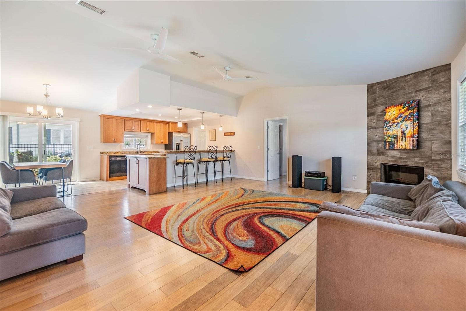 Beautifully updated open concept living space featuring vaulted ceilings, glass sliders to the back patio, a corner fireplace, and gorgeous wood floors.