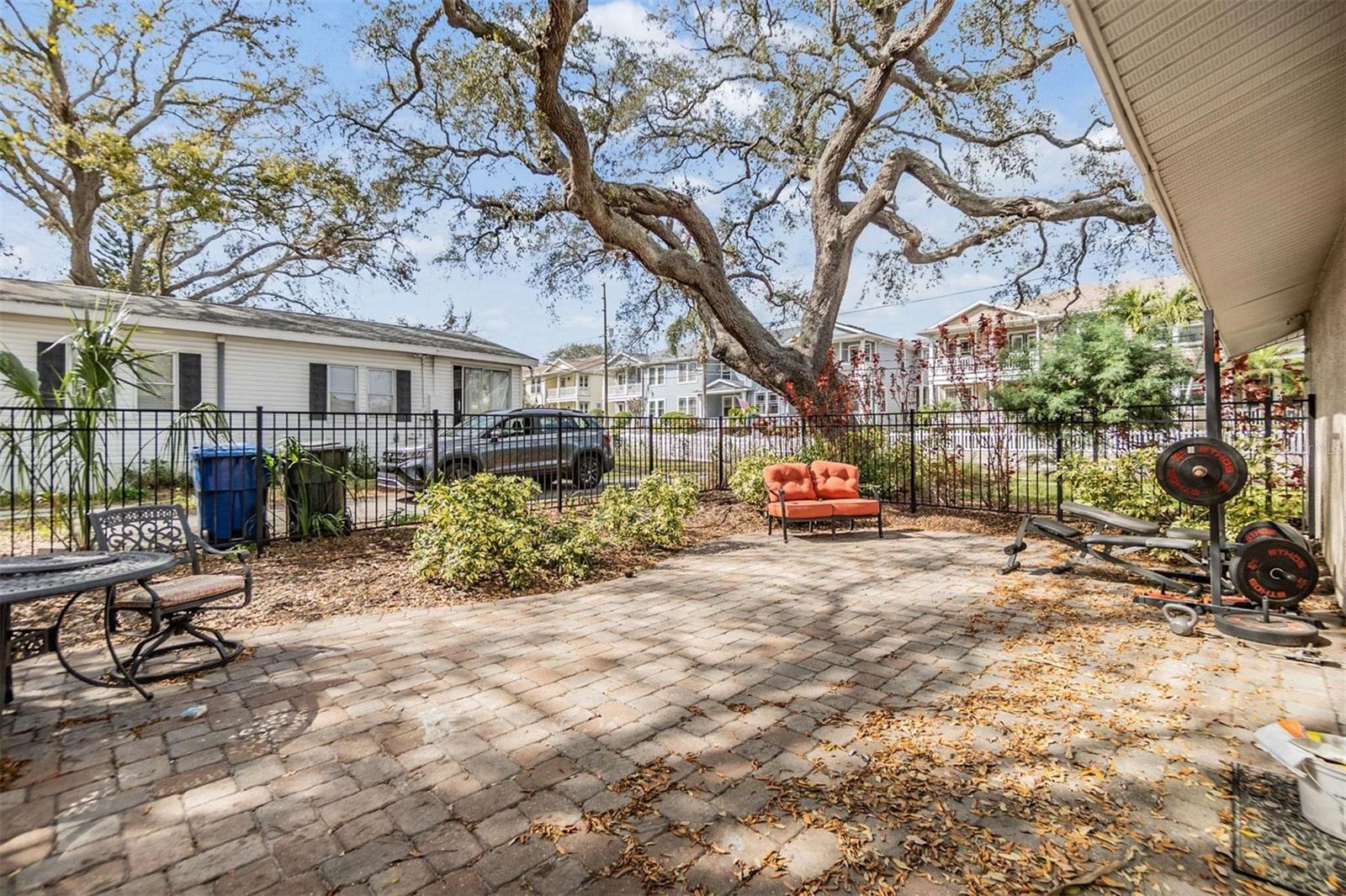 Park-like setting for back yard patio with pavers and wrought iron fence.