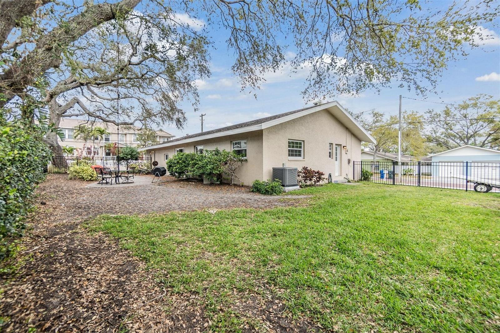 Park-like setting for back yard patio with pavers and wrought iron fence.