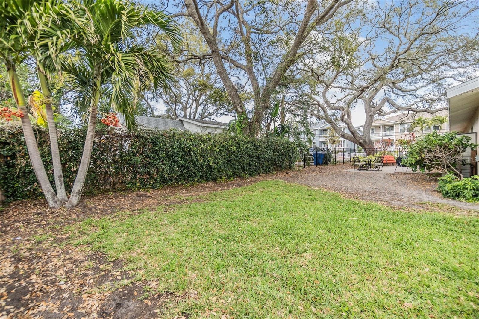 Park-like setting for back yard patio with pavers and wrought iron fence.