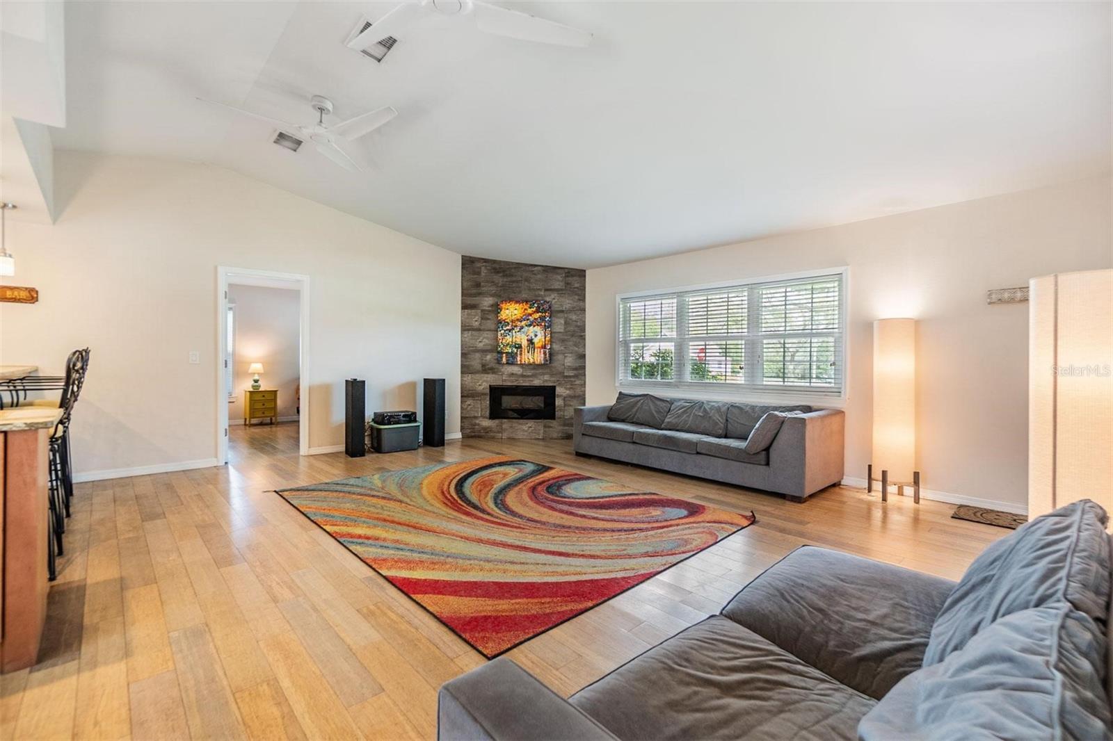 Beautifully updated open concept living space featuring vaulted ceilings, glass sliders to the back patio, a corner fireplace, and gorgeous wood floors.