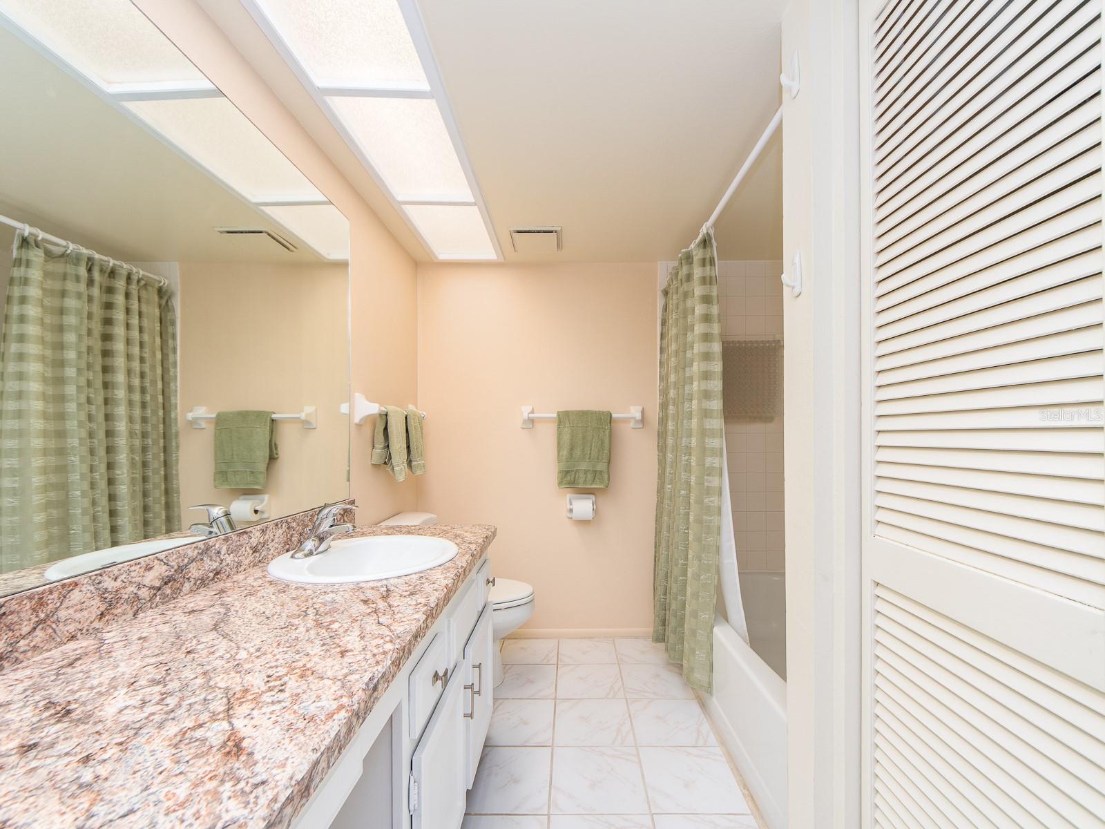 PRIMARY BATH WITH WOOD WHITE SHAKER CABINETRY AND A TUB SHOWER COMBINATION