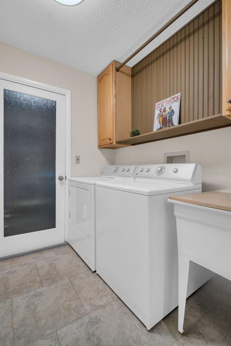 Indoor laundry with additional cabinet storage, utility sink, & garage access~