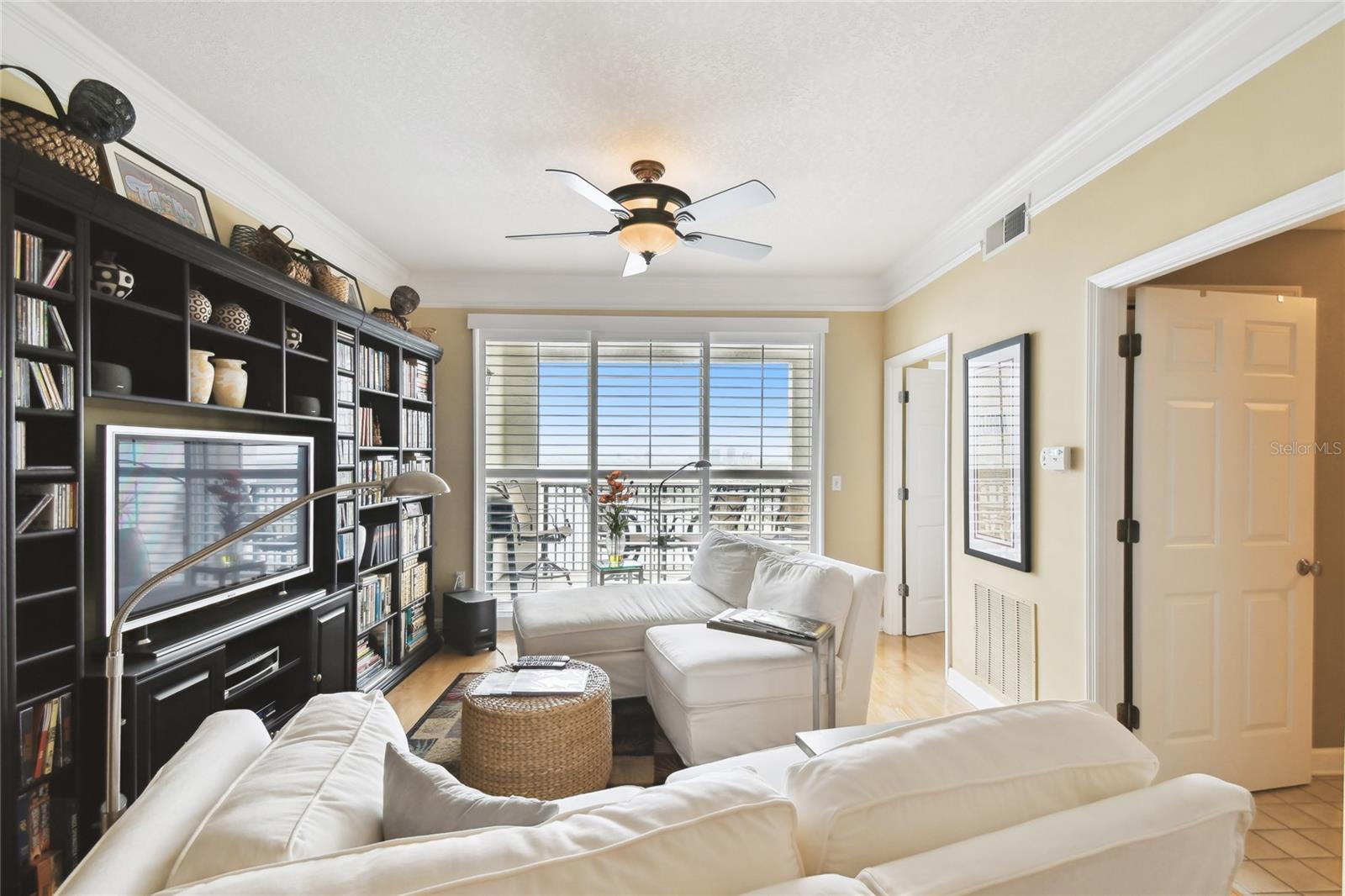 Bright living room with balcony access and custom entertainment center.