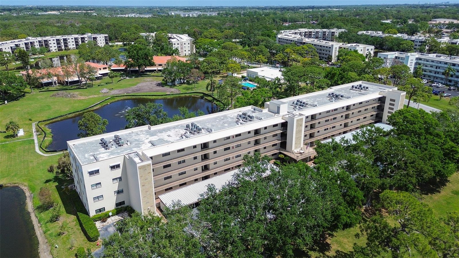 Aerial of building shows pool, pond, rec center, walking path