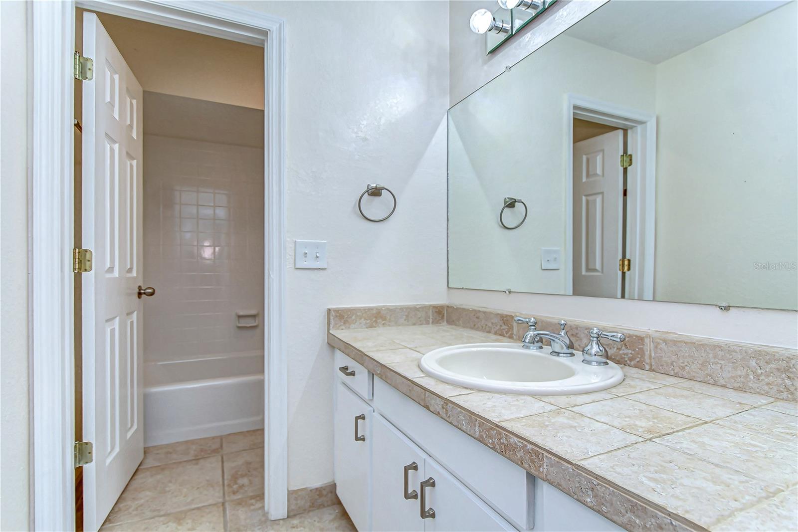 Step into a refreshingly spacious bathroom, featuring elegant tile work and ample storage beneath a wide countertop