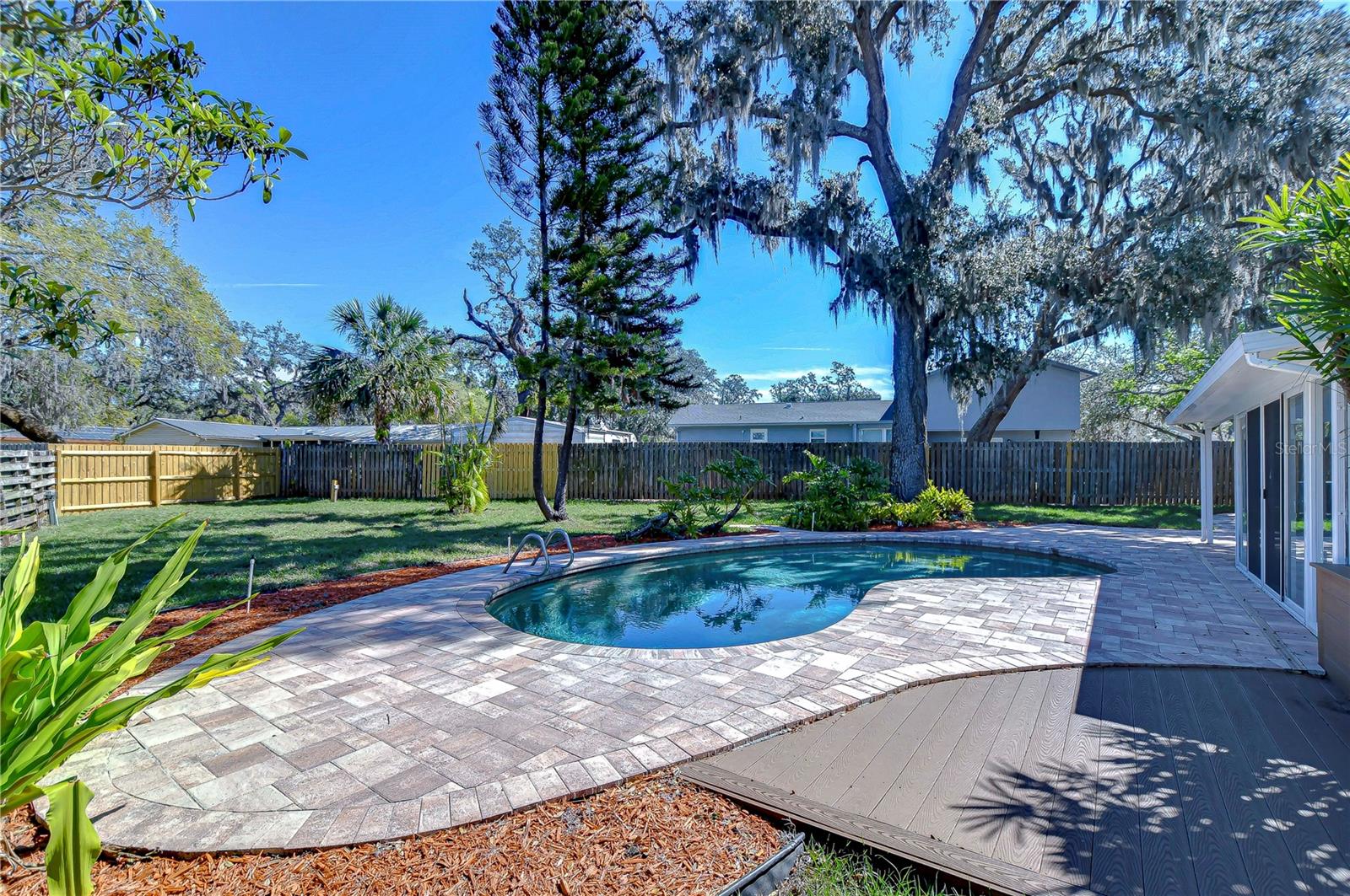 This elegant home boasts a charming poolscape surrounded by lush greenery, providing an enchanting oasis for relaxation and entertainment.