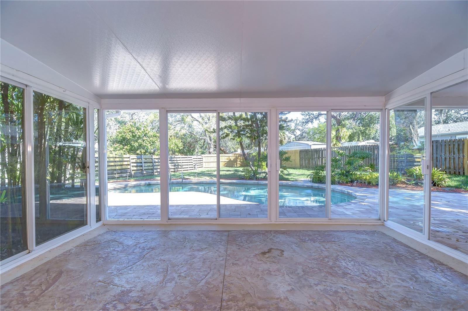 Step into this bright sunroom, where tranquility meets poolside elegance.