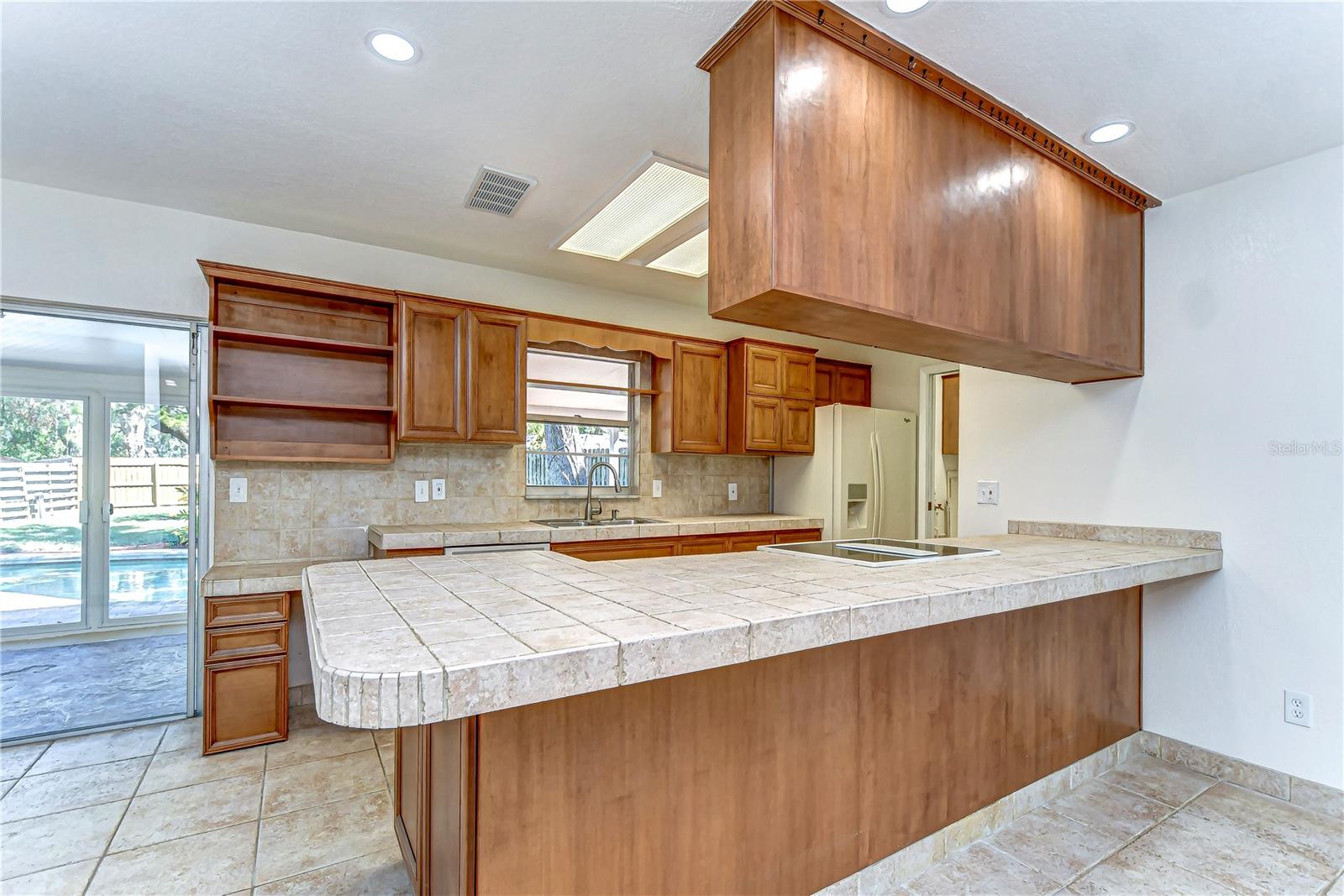 Discover the charm of a spacious kitchen featuring elegant wood cabinetry and expansive tile countertops.