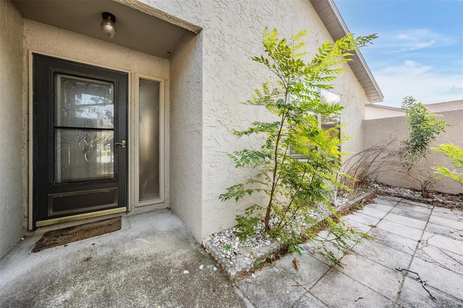 Front entry door with sidelight and a private patio.