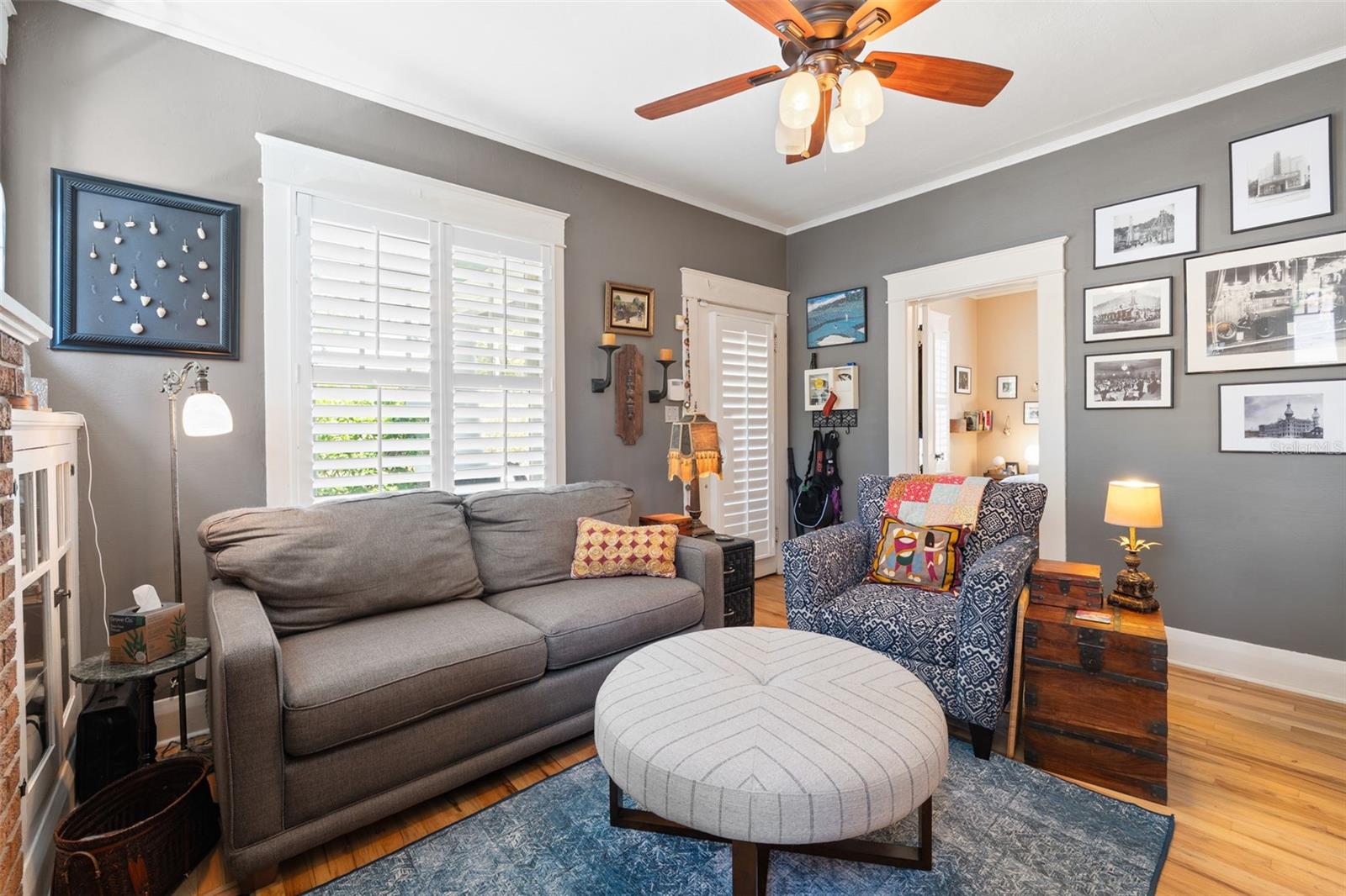 Lovely living room with brick fireplace, built-in cabinetry, original windows, and gleaming wood floors.