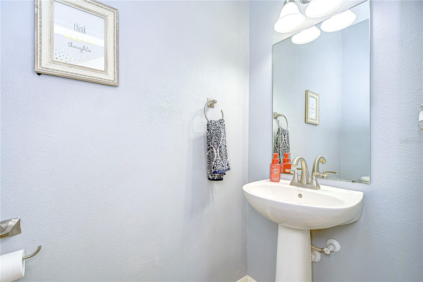 A sleek pedestal sink paired with a stylish faucet offers a touch of modernity