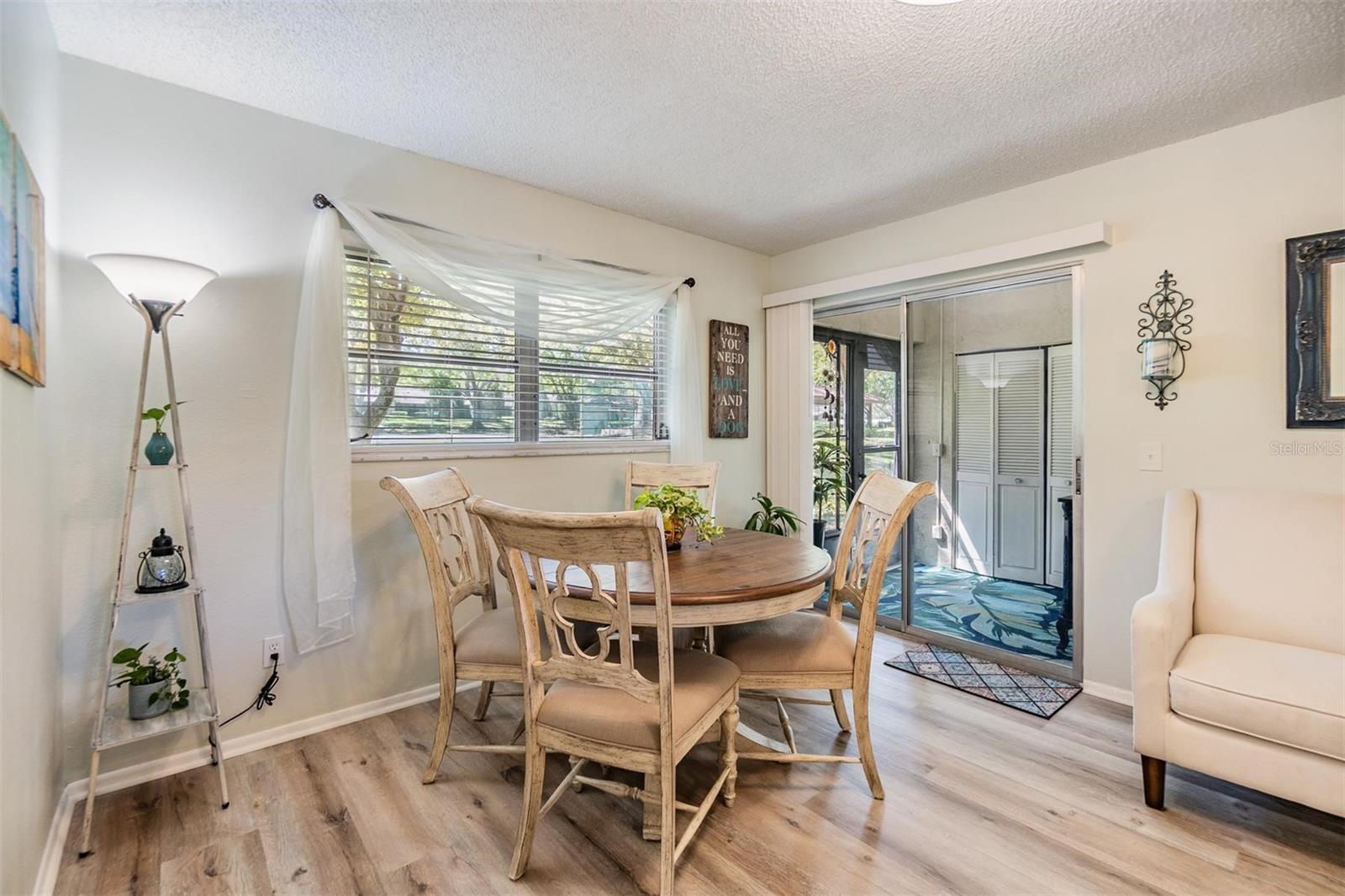 Light and bright living room and dining room with luxury vinyl plank flooring, pass through window to kitchen, and glass sliders out to the lanai.