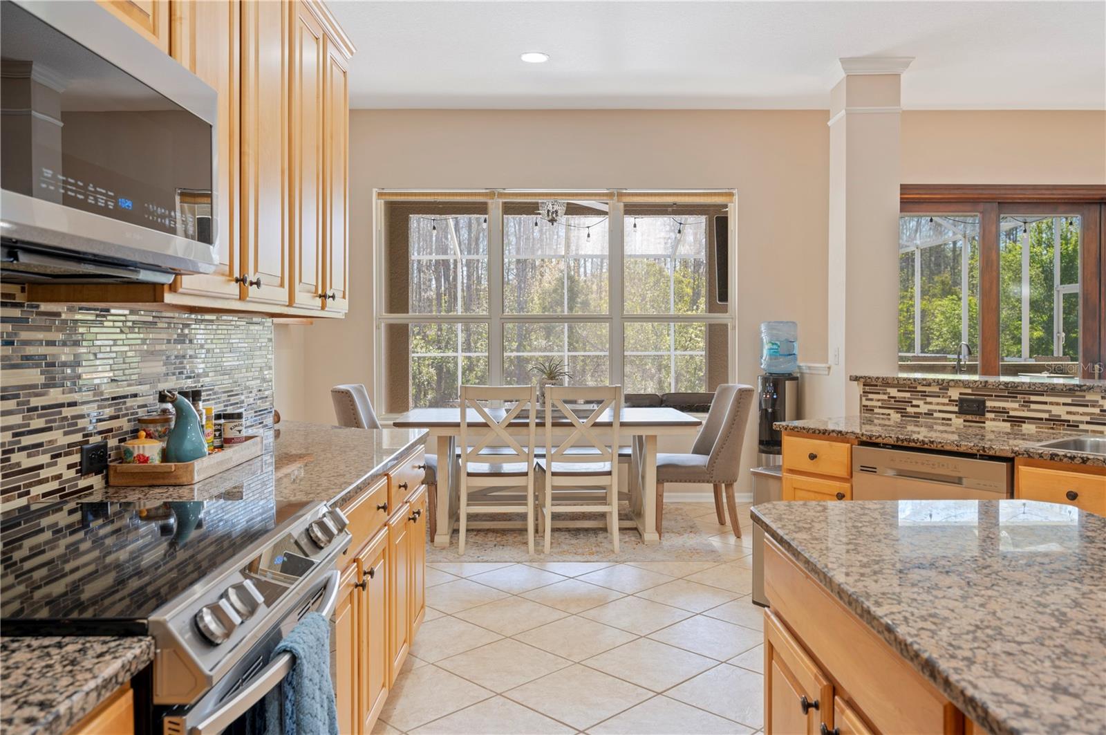 Kitchen opening to Nook with views of The pool and nature.